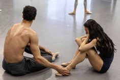 a man and woman sitting on the floor in front of each other with their legs crossed