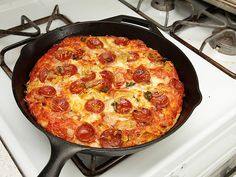 a pepperoni and cheese pizza in a cast iron skillet on top of a stove