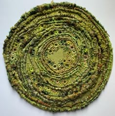 an image of a circular object made out of green and yellow yarn on a white surface