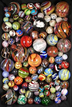 a box filled with lots of different colored marbles on top of each other,