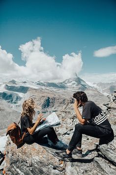 two people sitting on top of a rocky mountain