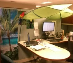 an office cubicle with palm trees and a computer on the desk in front of it