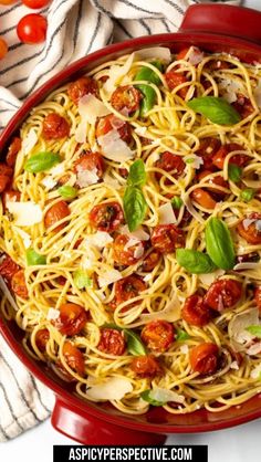 pasta with tomatoes, basil and parmesan cheese in a red dish on a striped towel