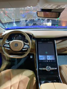 the interior of a car with an electronic display on the dashboard and leather seats in front of it