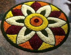 a circular design made out of flowers on top of a marble flooring area with red, yellow and white colors