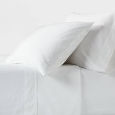 white sheets and pillows on top of a bed