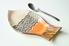 a spoon, fork and plate on a white surface with an intricately designed design