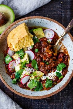 a bowl filled with chili, cornbread and vegetables