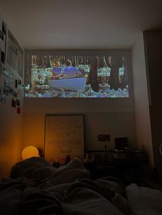 a person laying in bed watching a movie on the wall above them is a lamp