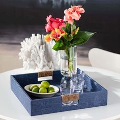 a vase with flowers in it sitting on a blue tray next to some green olives