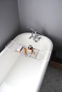 a white bath tub sitting next to a wooden basket filled with soap and lotion