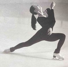 a female figure skating on the ice in a black and white photo with her arms outstretched