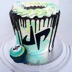 a cake with icing on it sitting on top of a glass plate next to a cupcake