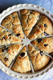 a white plate topped with blueberry scones on top of a marble countertop