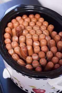 a crock pot filled with brown beans on top of a blue countertop next to a white cup