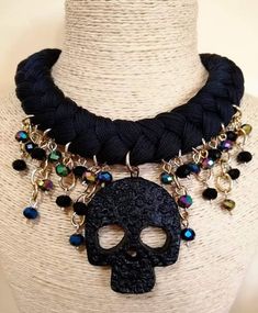 a black necklace with a skull on it and beads hanging from the neck, sitting on a mannequin