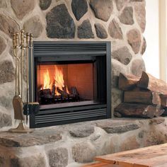 a fire place in a stone fireplace with logs on the side and a wooden table next to it