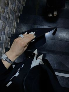 a woman with her hand on the edge of a black piece of paper next to stairs