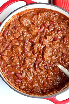 a pot filled with chili sitting on top of a red and white tablecloth covered plate