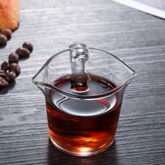 a glass cup filled with liquid next to coffee beans