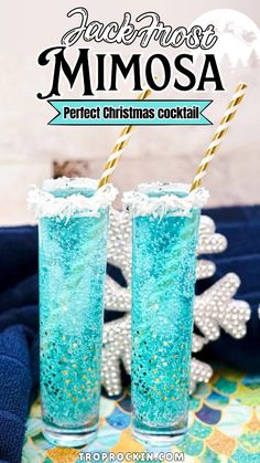 two glasses filled with blue liquid sitting on top of a table next to a snowflake