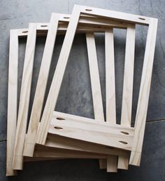 four unfinished pieces of wood sitting on top of a cement floor next to each other