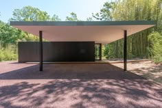 an empty covered parking lot in the middle of a wooded area with trees and bushes