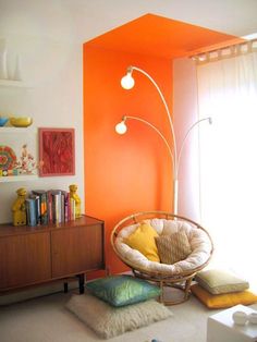 a living room with an orange accent wall and white rugs on the carpeted floor