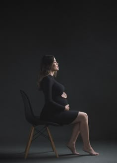 a pregnant woman sitting on a chair in the dark