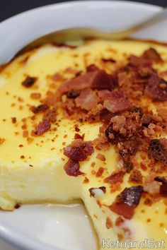 a white plate topped with a piece of cheesecake covered in bacon and other toppings