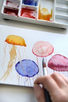 someone is painting jellyfish with watercolors on paper