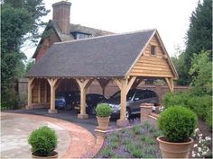 a wooden building with cars parked in it's driveway next to some bushes and trees