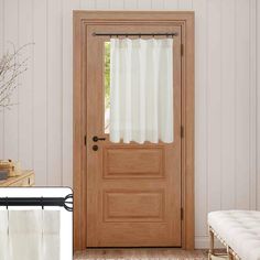 a wooden door sitting next to a window with white curtains on it's side