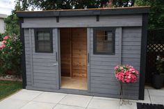 a small shed with the door open and flowers outside