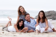 a family sitting on the beach with their arms around each other