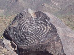 a large rock with a spiral design on it's side in the mountainside