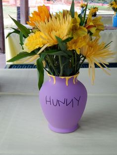 a purple vase filled with yellow flowers on top of a table