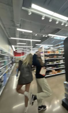 two people are walking through a grocery store with their feet in the air and one person is holding a shopping bag