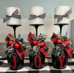 three black jars with red and white decorations on them sitting on a checkered tablecloth