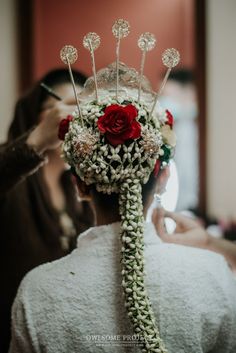 a woman is getting her hair done with flowers