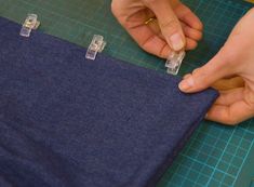 someone is cutting fabric with scissors on a piece of blue material that's being sewn together