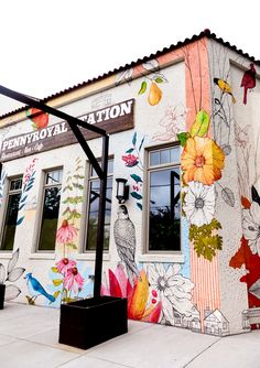 a building painted with flowers and birds on it's side, next to a street light