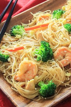 shrimp, broccoli and noodles with chopsticks on a wooden platter