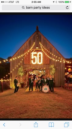 a group of people standing in front of a barn at night with lights on it