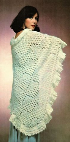 a woman is wearing a white shawl with crocheted fringes on it