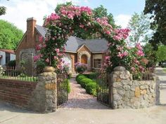 a house with pink flowers on the front gate