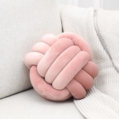 a pink pillow sitting on the back of a couch with it's arms wrapped in a knot