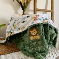 a green teddy bear blanket sitting on top of a table next to a potted plant