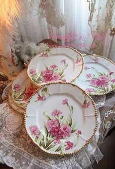 three plates with pink flowers on them are sitting on a table next to a window