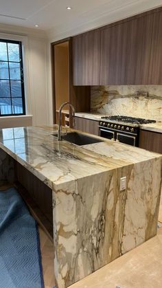 a kitchen with marble counter tops and an island in front of a window that is open to the outside